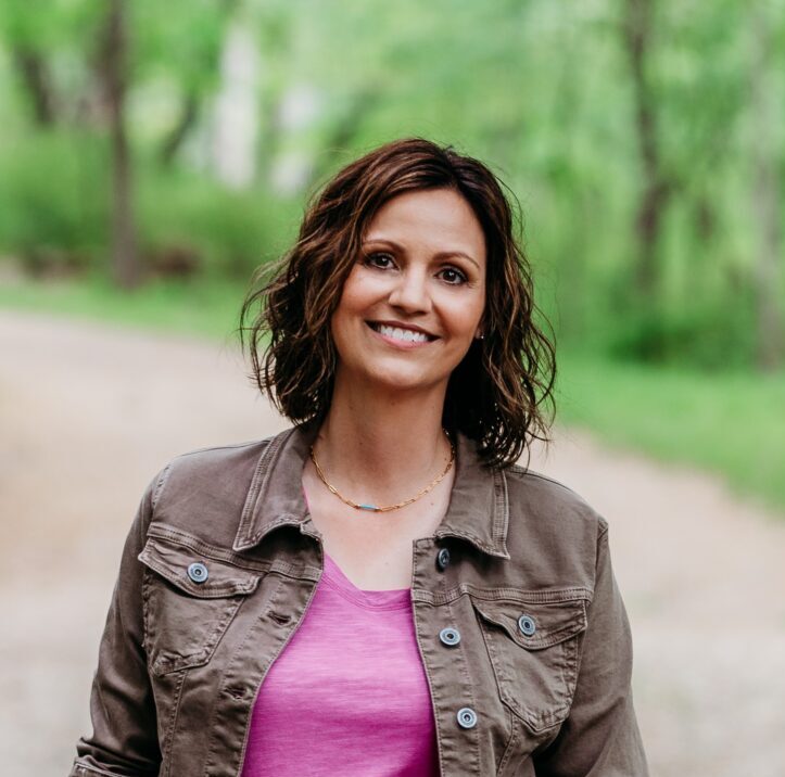 headshot of stephanie wearing a pink shirt standing on a nature trail smiling