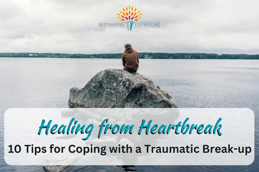 Man in orange jacket sitting on a rock in the middle of a lake healing from heartbreak. end id.